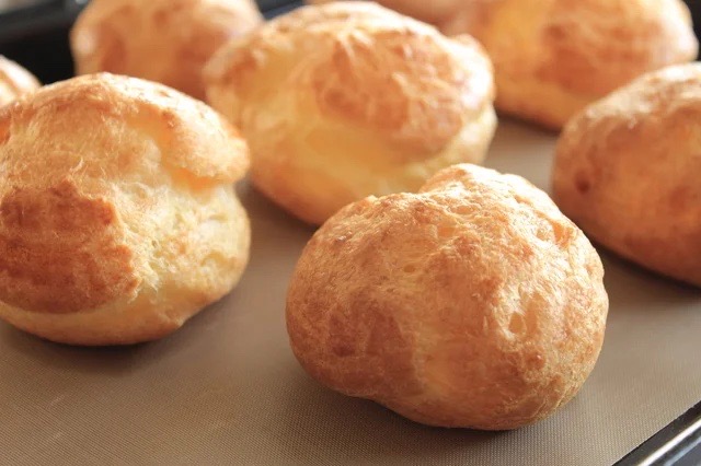 ふっくらと焼き上げられたシュー生地が並ぶ様子。セブンの「ダブルシュー」に使用される、軽やかで香ばしい生地のこだわりが感じられる一枚。