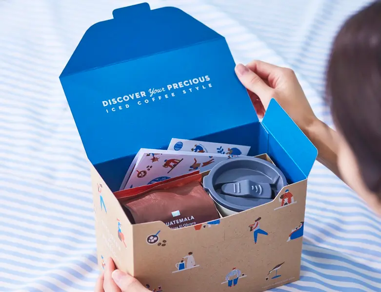 サマーボックスのフタを開けた場面。内側には「DISCOVER Your PRECIOUS ICED COFFEE STYLE」のメッセージ入り。限定アイテムが詰まった特別感のあるパッケージ。