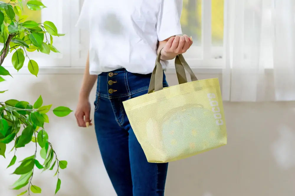 女性が手に持ったココスのメッシュトートバッグ。巾着が中に入っている様子