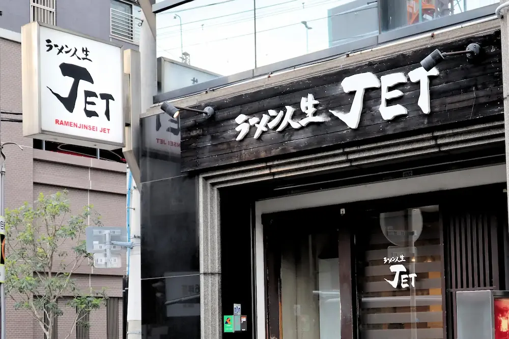 大阪・福島にある人気ラーメン店「ラーメン人生JET」の店舗外観。木目調の看板と白いロゴが印象的な佇まい。
