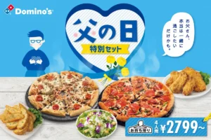 ドミノ・ピザの「父の日特別セット」ビジュアル。青い背景にハート型の「父の日」ロゴ、黄色いカーネーション、ピザ2枚とサイドメニューが並び、「お父さん、本当は一緒に過ごしたいだけかも。」のメッセージ付き。