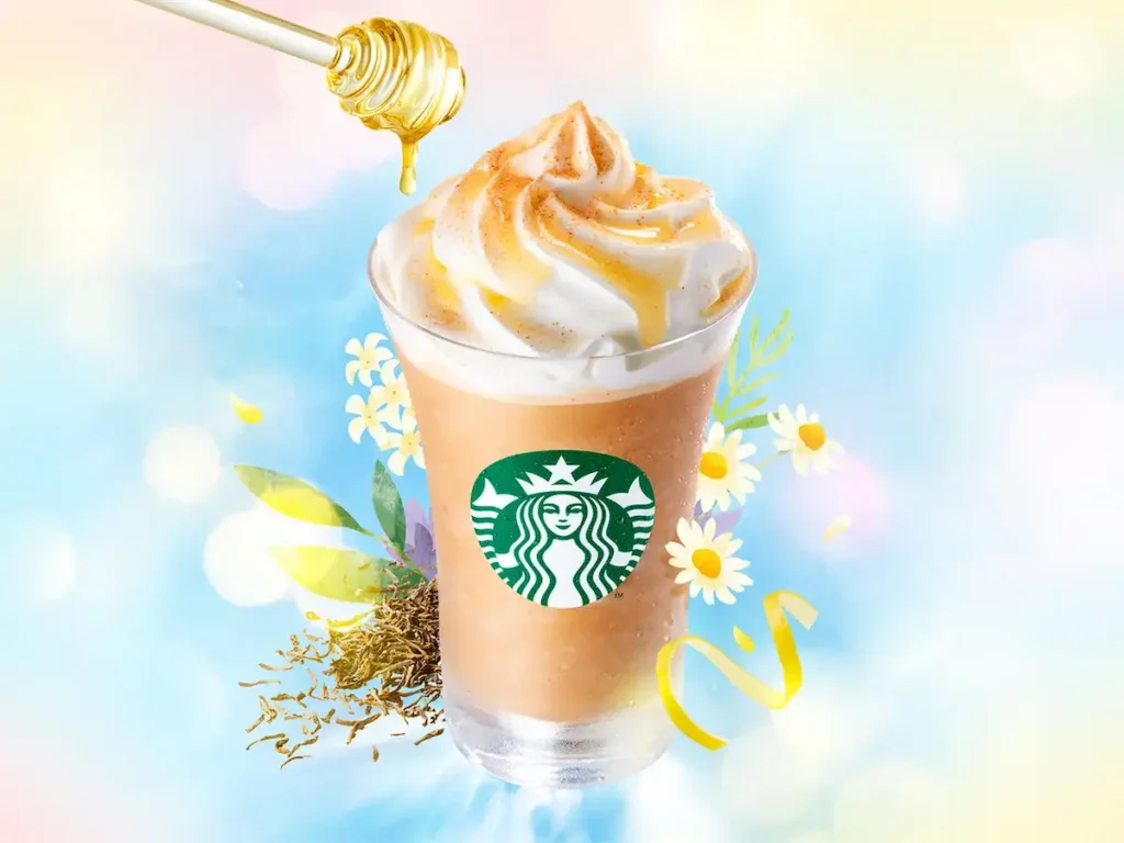 スターバックスの「アールグレイ ブーケ & ティー フラペチーノ®」に、はちみつがとろりとかかる様子。カモミールなどのハーブが背景に咲き、爽やかな初夏の雰囲気を演出。